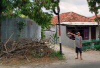 Warga menunjukkan tiang telkom yang diduga membahayakan pengguna jalan. 