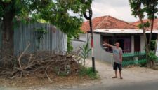 Warga menunjukkan tiang telkom yang diduga membahayakan pengguna jalan. 