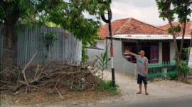 Warga menunjukkan tiang telkom yang diduga membahayakan pengguna jalan. 